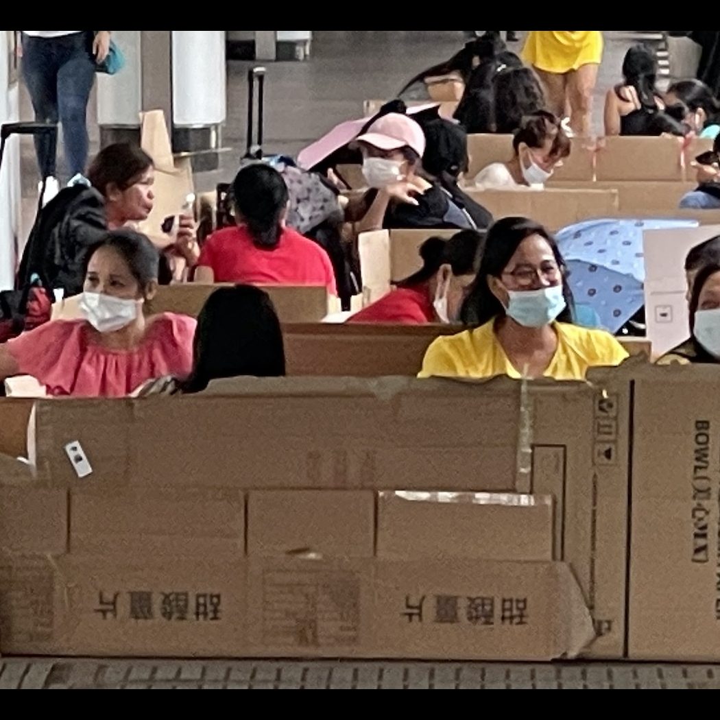 Hong Kong helpers sitting in cardboard boxes