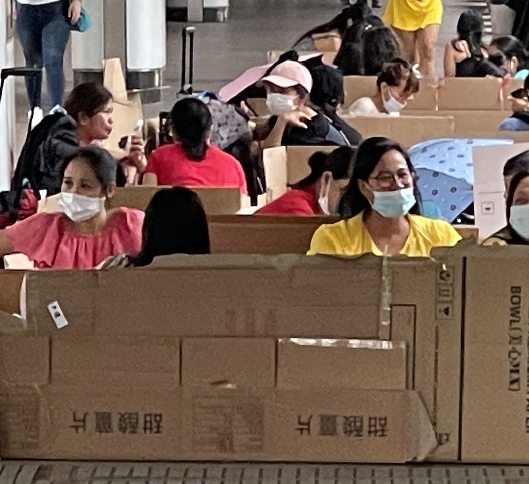 Hong Kong helpers sitting in cardboard boxes